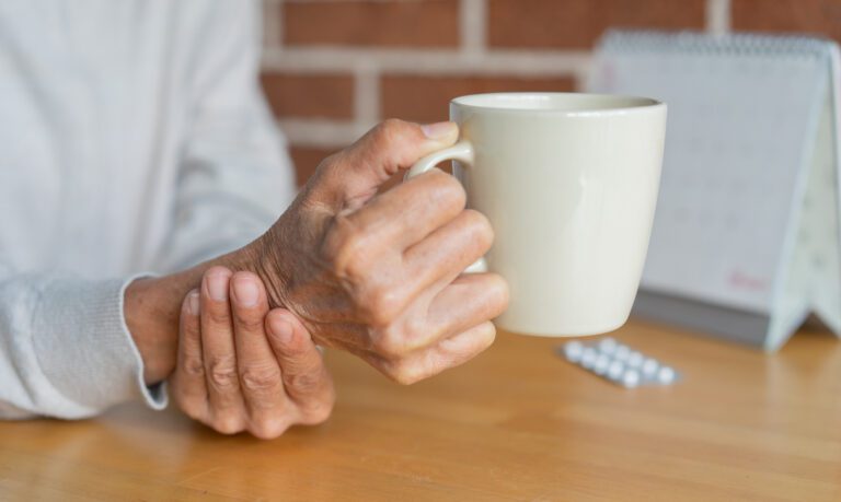 close up senior woman hand hold glass of waster for drink with unsteady at home for mature lifestyle and Parkinson's symptom concept Integrative root-cause rehabilitation for Parkinson’s Disease